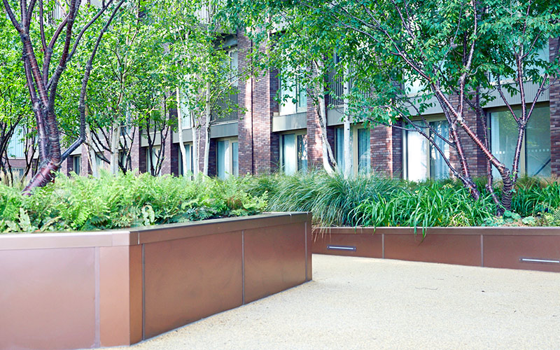 Planters in Bronze sandblasted PVD stainless steel in Embassy Gardens, part of the Ballymore Homes development, Nine Elms, Wandsworth, London, UK - Landscape Architect: Camlins; Hyland Edgar Driver - Landscape Designers: In-Ex Landscapes Planters in Bronze sandblasted PVD stainless steel in Embassy Gardens, part of the Ballymore Homes development, Nine Elms, Wandsworth, London, UK - Landscape Architect: Camlins; Hyland Edgar Driver - Landscape Designers: In-Ex Landscapes