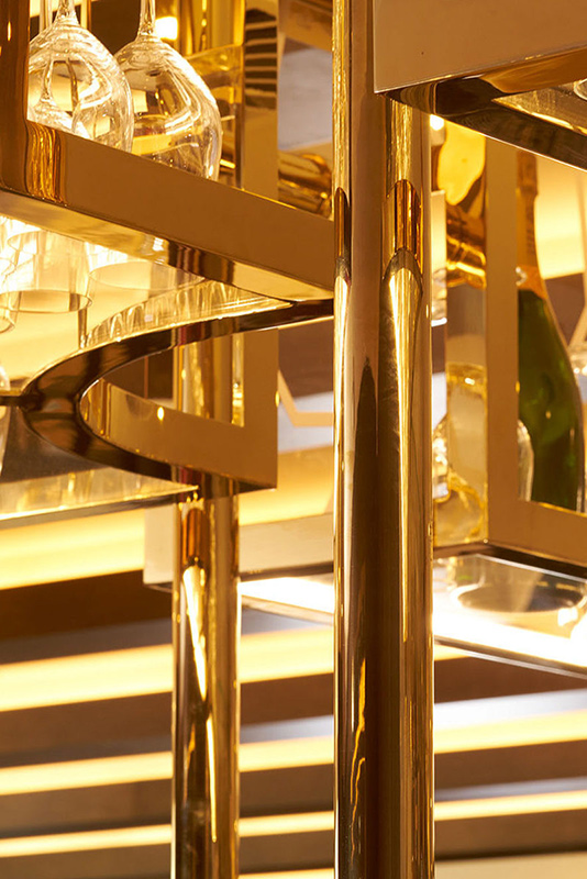 Detail of overhead bar rack in the Brasserie in Champagne Mirror PVD . The Devonshire Club Hotel Interior Design: March & White PVD coloured stainless steel: Double Stone Steel Europe Ltd