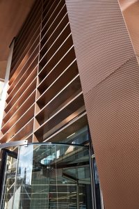 The brise soleil comprising sheet materal clad around a timber core, giving the impression of solid bronze fins. - 15 Fetter Lane, EC4A, London. - PVD coloured textured stainless steel in Chocolate for Brise soleil, canopy and column. - Architectural metalworks and PVD by John Desmond Ltd.