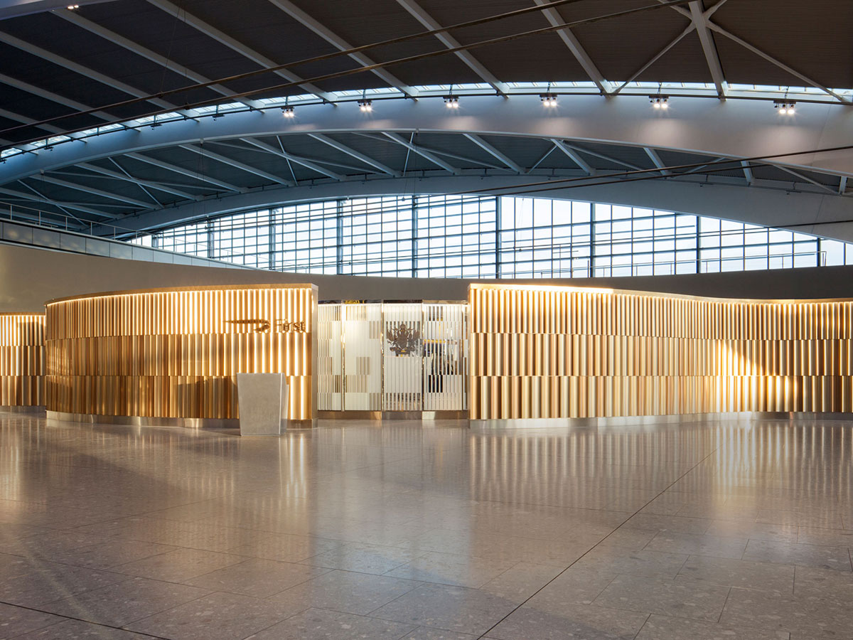 The reflective gold tones of the PVD coloured stainless steel are designed to stand out as a welcoming beacon within the neutral and beige tones of the rest of the terminal. - Architects/Interior Designers: Universal Design Studio - PVD Coloured Stainless Steel: Double Stone Steel Europe Ltd - Photography: Paul Greenleaf