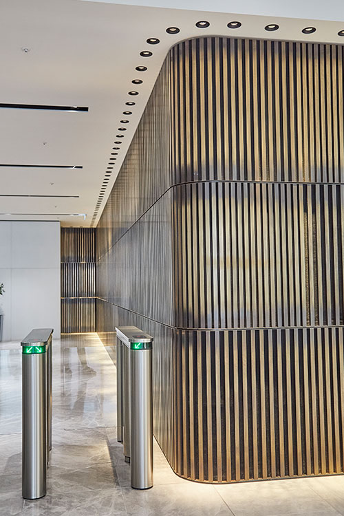 1 Broadgate Quarter, Snowden St, London, EC2A 2AW - Architects: John Robertson Architects. - Stainless Steel Canopy: Double Stone Steel Europe Ltd. - The narrow brass bars cladding the feature wall as it curves around to the rear of the space create a shimmering and timeless detail, slightly Oriental in its style.